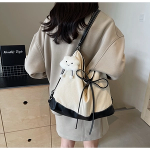 Detail of canvas tote bag featuring contrast leather trim and a cute cloud plush charm