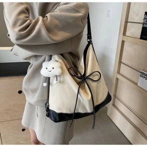 Close-up of canvas tote bag with black leather straps and cute plush cloud pendant