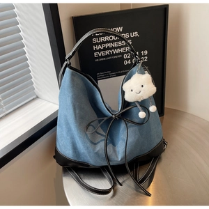 Detail of blue denim tote bag featuring black leather trim and white cloud charm