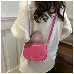 Rear view of model holding rose pink faux leather saddle bag with gold hardware