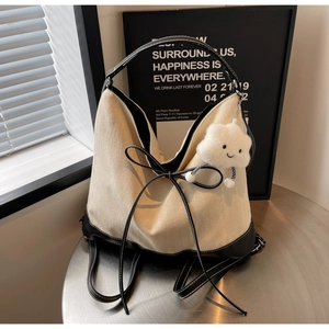 Detail of canvas tote with black leather trim and white cloud charm on metal table