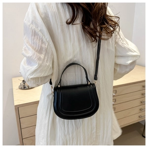 Vista posteriore di una modella con borsa a sella nera a tracolla e cuciture di dettaglio