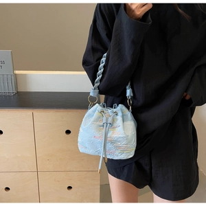 Detail of light blue bucket bag with rainbow wave embroidery and woven drawstring handle