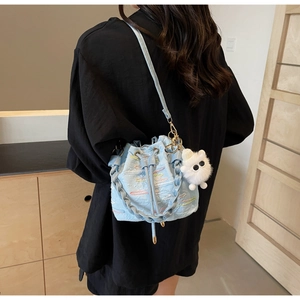 Detail of light blue bucket bag featuring colorful embroidery and a plush pendant