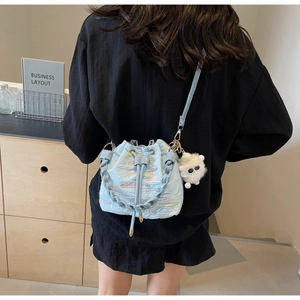 Detail of light blue bucket bag with colorful wavy stitching and plush charm