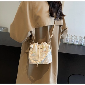 Detail of white drawstring bucket bag with colorful wavy stitching and woven handle