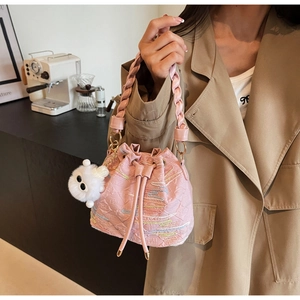 Detail of pink embroidered bucket bag with woven handle and plush doll charm