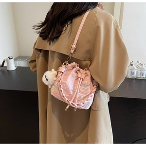 Close-up of pink drawstring bucket bag with floral embossing and cute plush bear charm