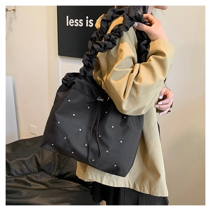 Detail of black pleated tote bag featuring sparkling rhinestones and a drawstring closure