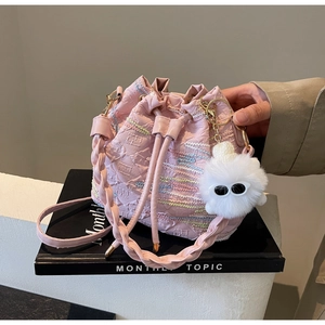 Close-up of pink drawstring bucket bag featuring embroidery texture and plush monster charm