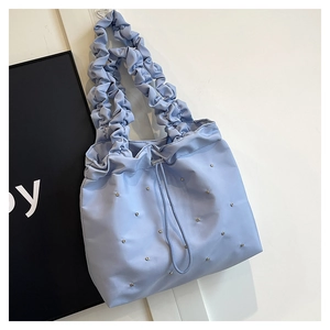 Close-up of pleated handle and metallic studs on light blue nylon tote bag detail