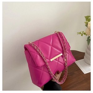Detail of hot pink quilted crossbody bag with gold-tone hardware and chain strap