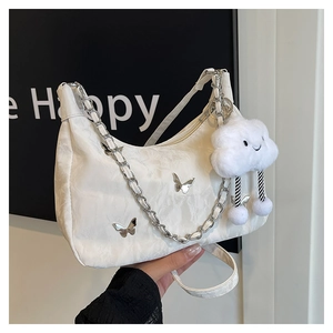 Détail macro du sac hobo blanc avec breloque papillon argentée et nuage en peluche