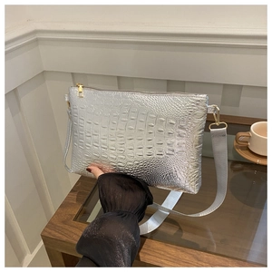 Detail of silver crocodile pattern envelope bag with golden zipper and wide strap
