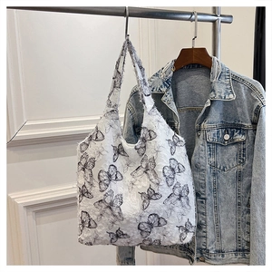 Detail of white butterfly print tote bag with frayed edges and distressed fringe texture