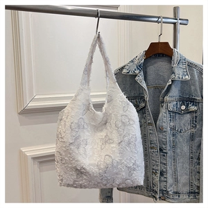 Close-up of white canvas tote bag with textured 3D butterfly lace and jacquard details
