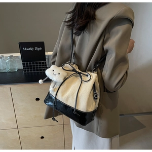 Close-up of canvas bucket bag with bow detail and soft cloud charm on a shoulder strap