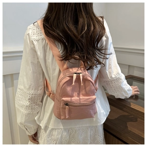 Vue arrière d'un mannequin portant un mini sac à dos en nylon rose et une blouse