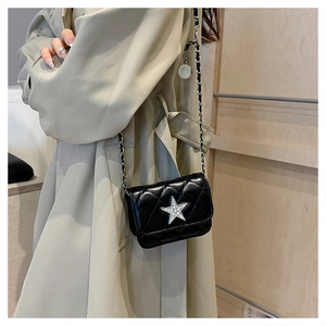 Detail of black quilted crossbody bag with silver star ornament and chain strap