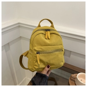Close-up of mustard yellow nylon mini backpack with top handle and double zipper details