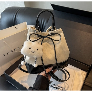 Detail of drawstring bucket bag with plush charm and gift packaging