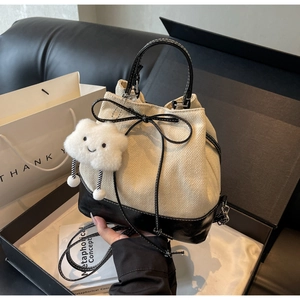 Detail of two-tone bucket bag with drawstring closure and cute cloud plush charm