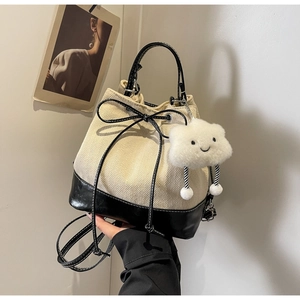 Detail of canvas bucket bag with black leather trim and cute plush cloud charm