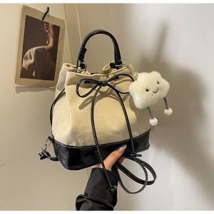 Detail of herringbone bucket bag with leather base, drawstring bow, and cloud charm