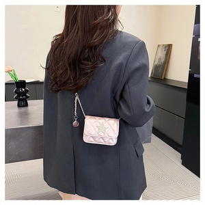 Back view of model wearing a pink quilted mini chain bag with star charm and metallic finish