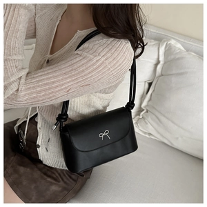 Détail du sac à bandoulière en cuir noir avec nœud argenté et sangle d'épaule nouée