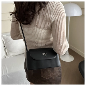Détail du sac bandoulière noir avec nœud en métal argenté sur similicuir mat de qualité