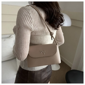 Détail du sac beige avec fermoir nœud en métal argenté sur un cuir PU souple et lisse