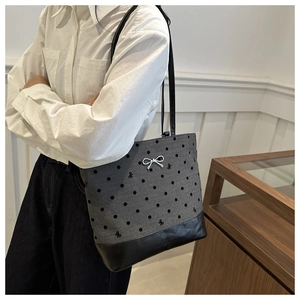 Close-up of gray polka dot bucket bag with black leather patchwork and silver bow detail