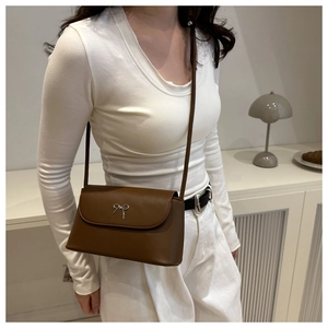 Vue détaillée d'un sac bandoulière marron vintage en cuir avec un n&oelig;ud argenté sur le rabat