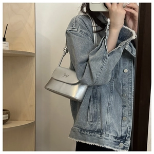 Détail du sac à main argenté métallisé avec nœud embossé et bandoulière en cuir fin