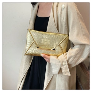 Close-up of gold envelope clutch bag with crocodile texture and metallic trim
