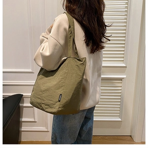Détail du grand sac cabas en nylon vert olive avec une étiquette tissée noire sur le côté