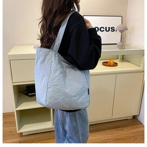 Détail du sac cabas plissé bleu clair montrant la texture et la bandoulière souple