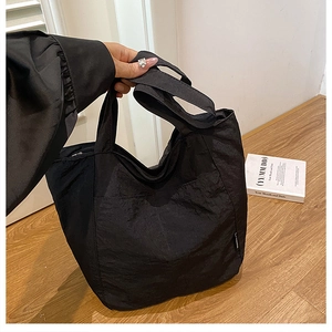 Detail of black nylon tote bag featuring a unique crinkled texture and large front pocket