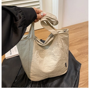 Macro detail of beige wrinkled nylon tote bag showing side pocket and durable strap