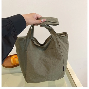 Detail of army green waterproof nylon tote bag with pleated texture and front pocket
