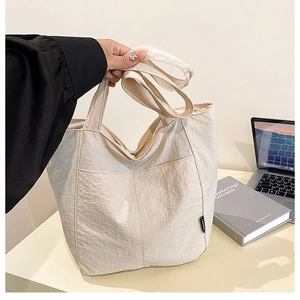 Detail of beige nylon tote bag with pleated texture and black Fashion fabric label
