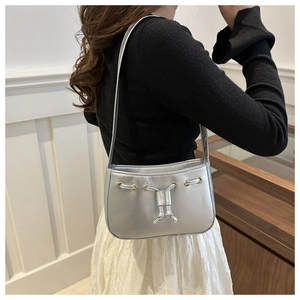 Silver underarm bag with metallic finish and gold eyelets worn by a model