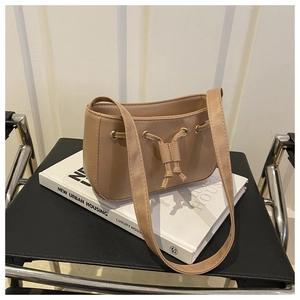 Close-up of light brown leather drawstring bag on books with metal ring details