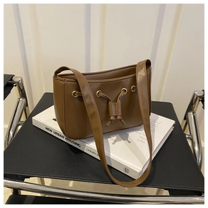 Close-up of brown faux leather shoulder bag featuring drawstring detail and metal eyelets
