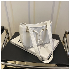 Detailed shot of white faux leather bag with decorative drawstrings and golden eyelets