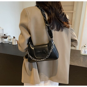 Detail of black leather shoulder bag with bow decor and floral silver chain strap