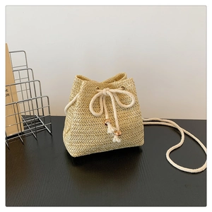 Detailed view of woven straw bucket bag with cotton drawstring and wooden beads