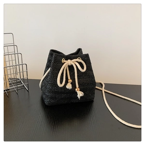 Close-up of black straw woven bag with cream cotton drawstrings and wooden beads
