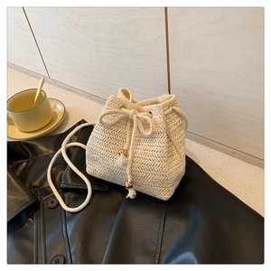 Detail of hand-woven beige straw bucket bag with drawstring closure and wooden beads